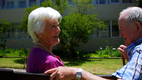 side view of active caucasian senior couple interacting with each other in the garden of nursing hom