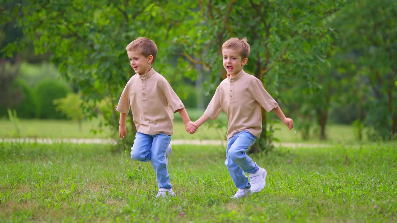 Ragazzi giovani e felici che si tengono per mano e corrono in un parco verde.