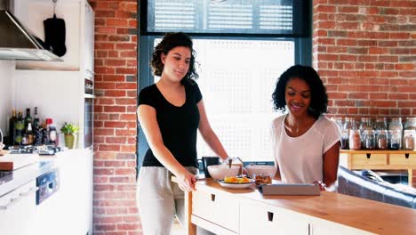 lesbian couple using digital tablet while having breakfast