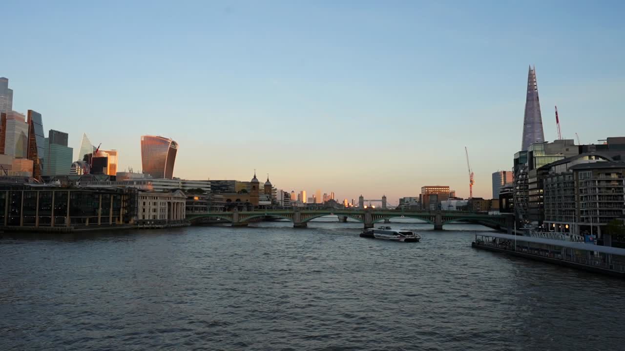 Uber boat navigates Thames at sunset between The Shard and London's financial district