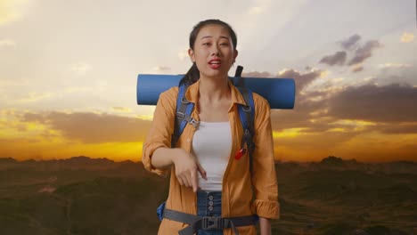 woman hiker pointing at sunset
