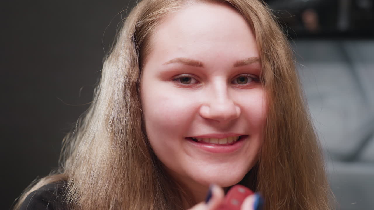 Zoom in portrait light skinned girl in kitchen, smiling as she playfully turns knife and blows kisses toward camera, soft lighting on hair, friendly expression, modern background, casual home mood