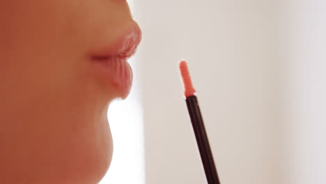 Close-up-of-woman-applying-lip-gloss-on-her-lips-in-bathroom