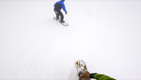 snowboarder follows his fellow riding ahead. winter sports activity in the mountains.