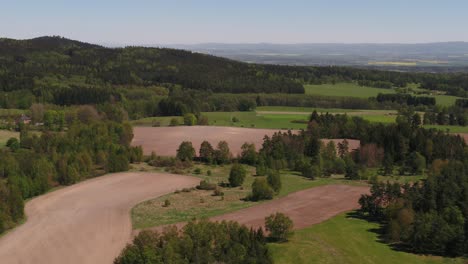 wide aerial shot of rural landscape with green fields and forest near prague, captured on a sunny day
