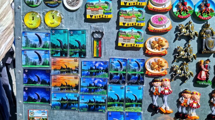 A vibrant collection of Birzai, Lithuania souvenir magnets featuring landmarks, foods, and traditional costumes arranged on a metal display at a market