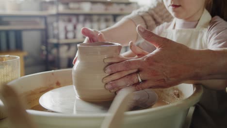 grandmother teaches her granddaughter working on a pottery rotating wheel