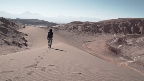 hombre a cámara lenta caminando en las dunas de arena del desierto