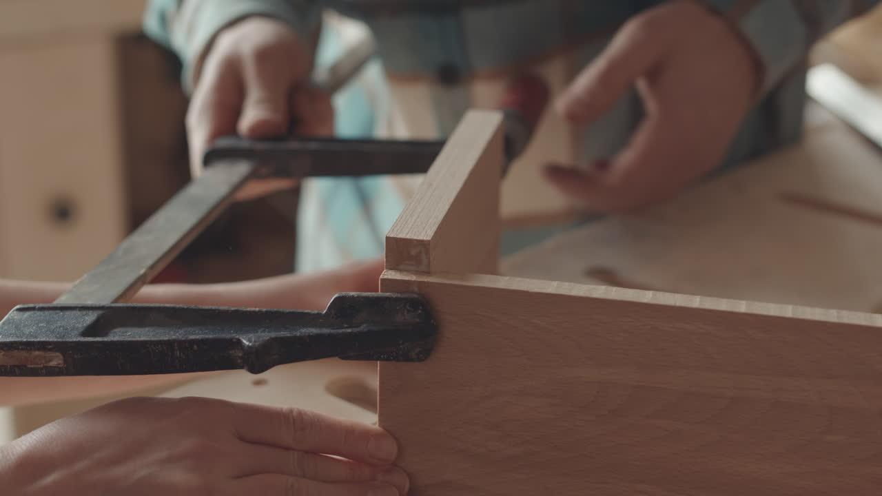 Two Joiners Fastening Planks Together Using Carpentry Instrument