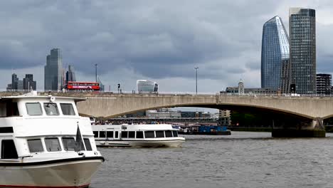 Barcos-En-El-Río-Támesis-Con-Tráfico-Cruzando-El-Puente-De-Waterloo-Con-Vistas-Al-Horizonte-De-Canary-Wharf-En-Londres,-Reino-Unido