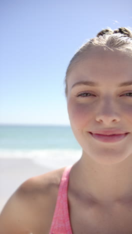 vertical video: smiling woman enjoying sunny day at beach, relaxing by ocean