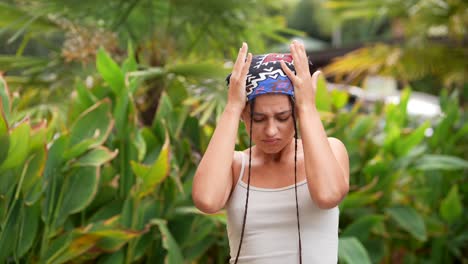 mujer con la cabeza envuelta y trenzas en un jardín tropical