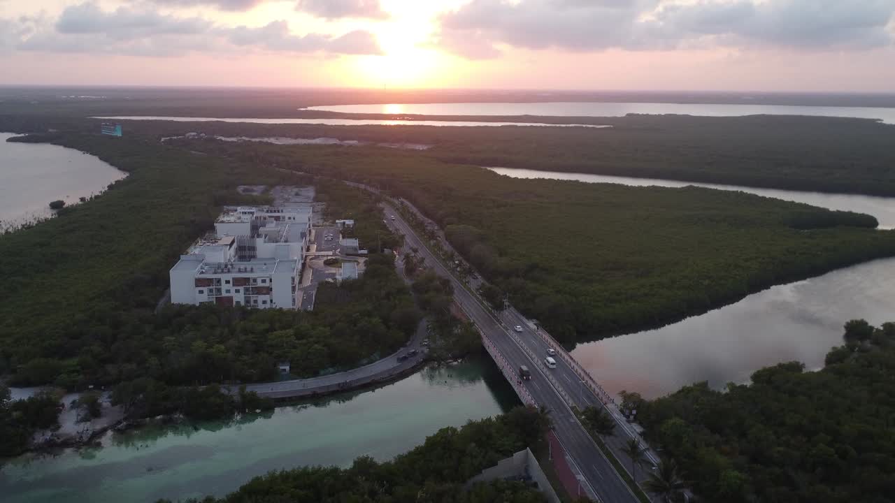 drone aéreo al atardecer disparado sobre el puente de punta nizuco por la laguna nichupte en cancún, méxico, rodeado de sistemas fluviales y vegetación