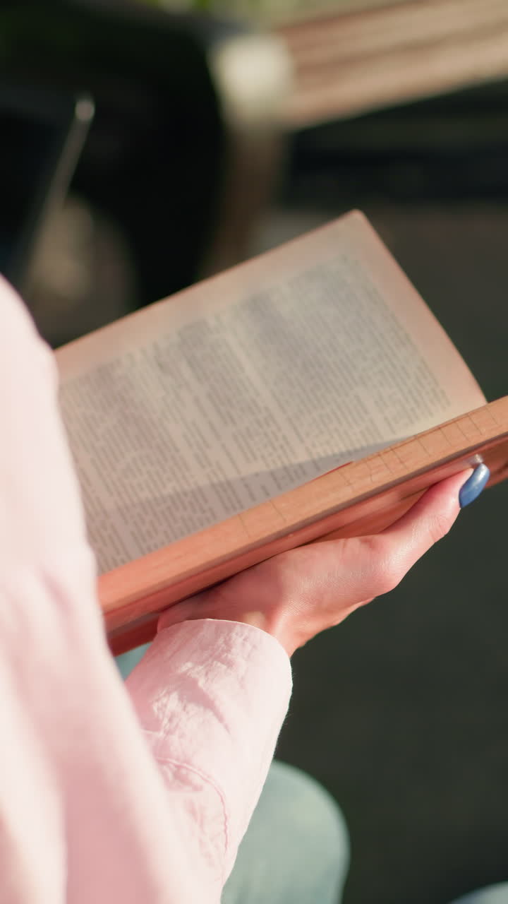close up de la dama en rosa arriba sosteniendo el libro mientras está sentado al aire libre estudiando, con sombras visibles y banco borroso en el fondo