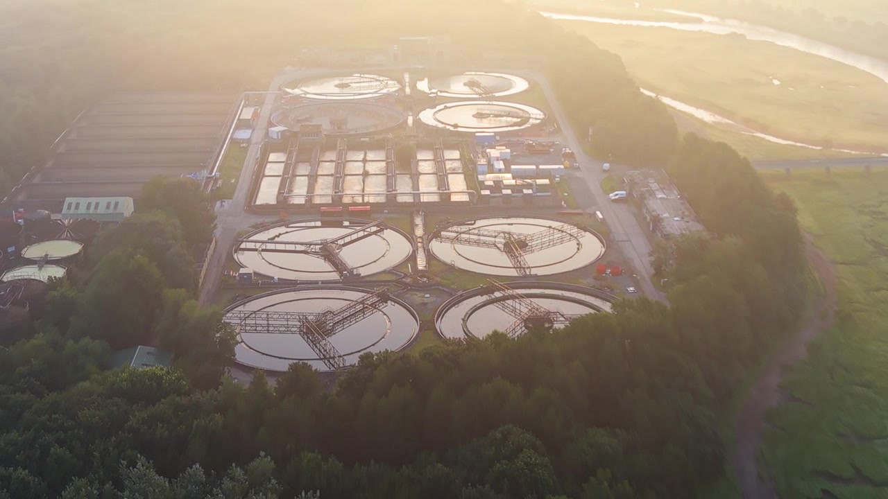 Retreating Aerial Water Treatment Plant and wastewater recycling facility at sunrise. Golden Hour Misty Glow. Clean tech, sustainability, and environmental engineering concept.