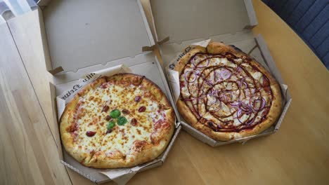 the handheld shot of delivered italian pizza in a cardboard box on the table at home