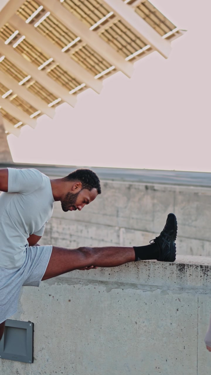 Man Stretching Leg on Concrete Wall During Outdoor Workout