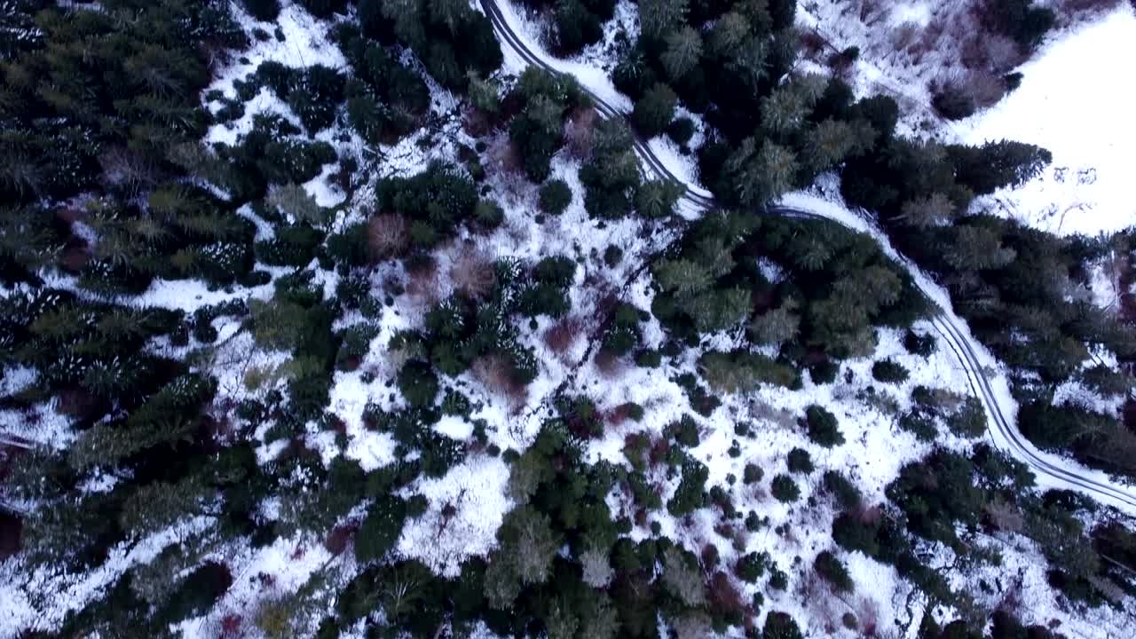 Vista aerea dall'alto di una strada di montagna tortuosa tra foreste innevate durante l'inverno nelle Alte Vosgi, Francia