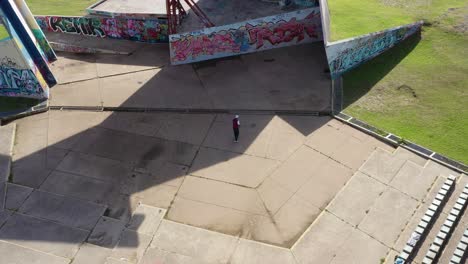 man playing fronton tennis on a graffitied wall, public park, modern urban amphitheater