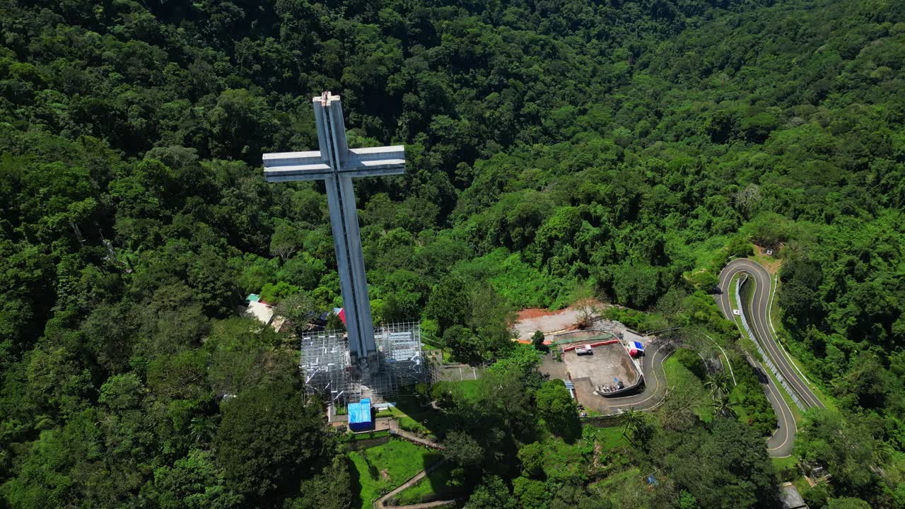 Tilt‑down aerial revealing the towering Mt. Samat National Shrine atop a lush forested hill, framed by sweeping valleys and distant mountains in Pilar, Bataan, Philippines