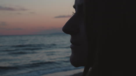 Primerísimo-Plano-De-Una-Chica-Parada-En-La-Playa,-Mirando-Al-Océano-Al-Atardecer-Y-Pensando-En-Recuerdos