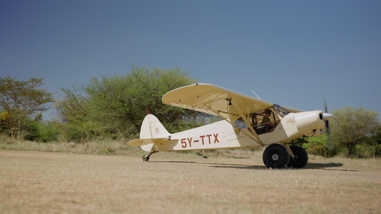Lite propellfly tar av fra en gressbelagt flystripe.