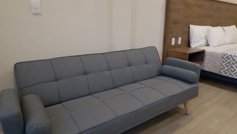 grey couch next to the bed inside the hotel