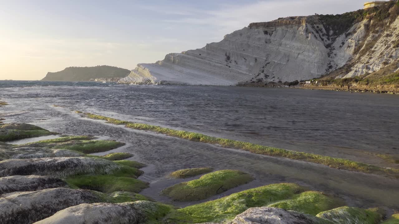 Scala dei Turchi ad Agrigento, Sicilia, al tramonto romantico con onde marine e pietre con muschio verde