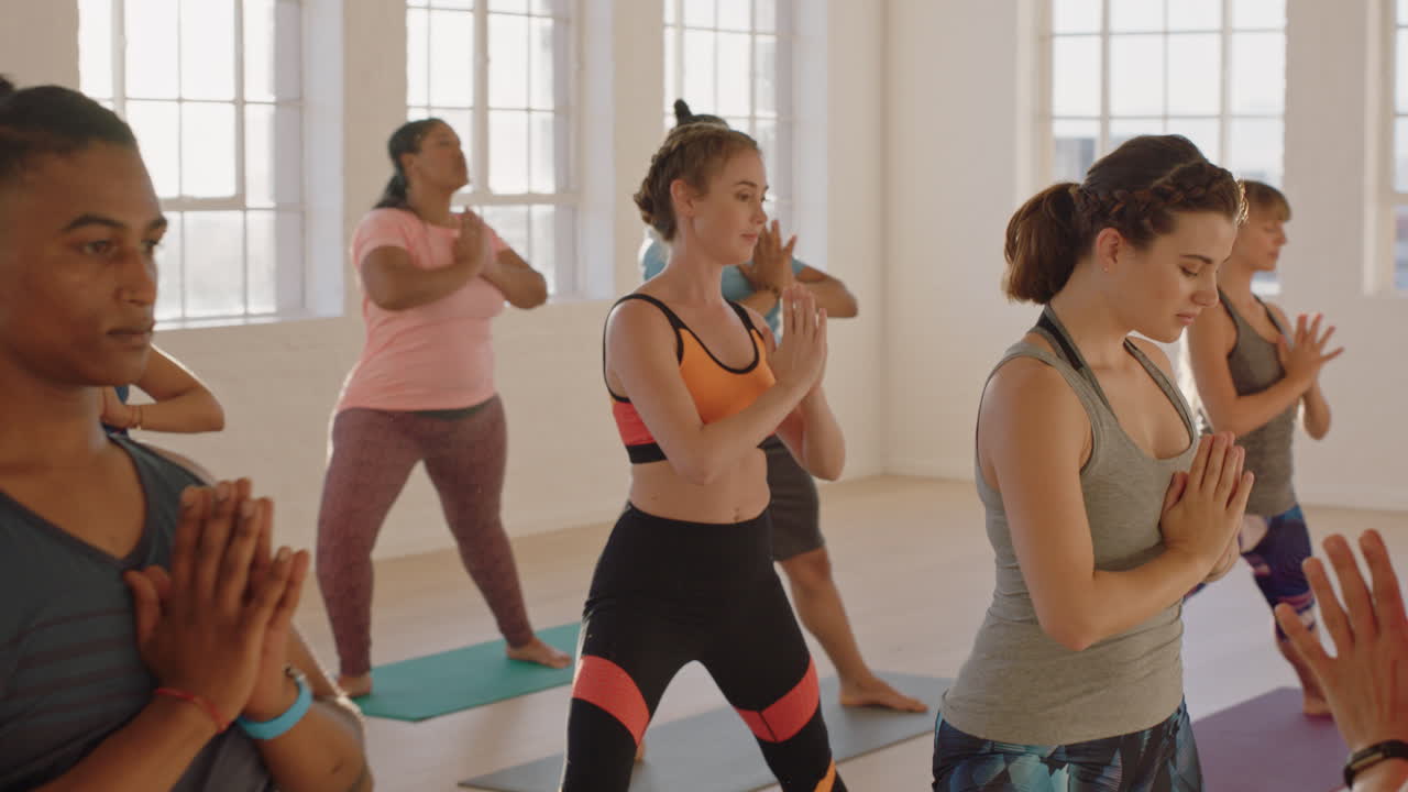 일출 때 강사와 함께 피트니스 스튜디오에서 운동을 즐기며 기도하는 젊은 건강한 사람들의 요가 수업
