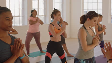 yoga class of young healthy people practicing prayer pose enjoying exercising in fitness studio with instructor at sunrise