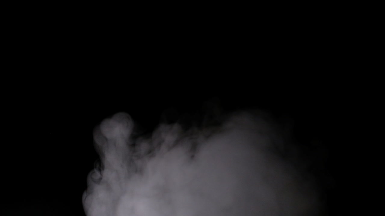 은 증기가 에서 회전하고 올라갑니다. 은 연기가 큰 비에서 올라옵니다. 프레임 뒤에 위치하고 있습니다. 고립 된 무결 루프 검은 배경.