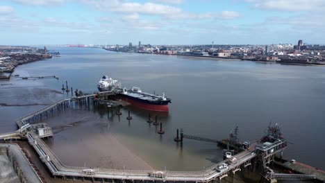 international crude oil tanker ship loading at refinery harbour terminal aerial view push in