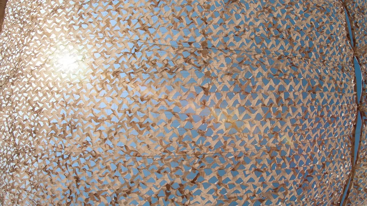 el sol brilla a través de la red de sombrilla textil en un día caluroso de verano