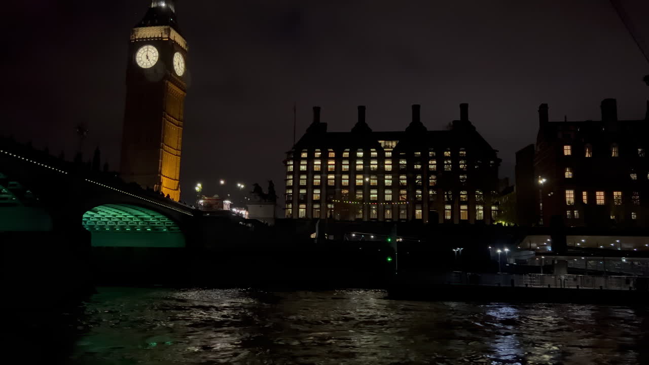 View from a moving boat of the Big Ben and the buildings alongside the Thames River in the evening in London, England