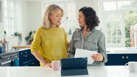 worried same sex mature female couple using digital tablet at home to check domestic finances