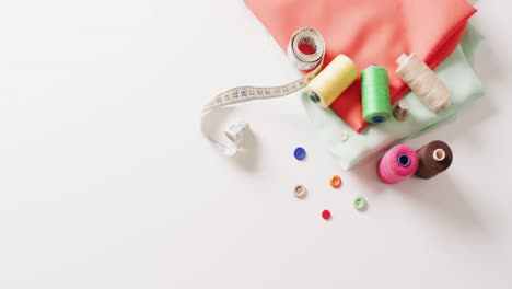 video of folded fabric with tape measure and cotton reels on white background with copy space