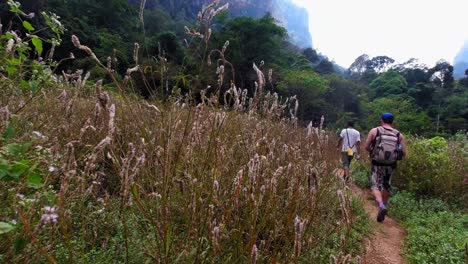 태국 카오 속(khao sok)에 있는 무성한 녹색 자연 공원으로 향하는 길고 좁은 길을 걷고 있는 관광객 그룹 - 롱 샷