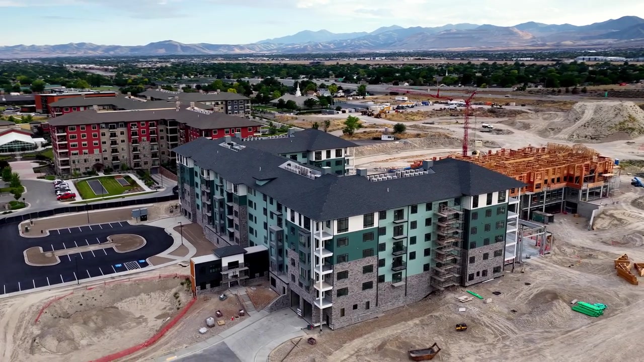 Completed apartment building with parking area, entrance, active wood-frame construction and earthworks in Taylorsville, Salt Lake County, Utah, Salt Lake Valley, Wasatch Range, drone parallax.