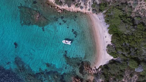 barco solitario en aguas turquesas claras y transparentes en la costa de cerdeña