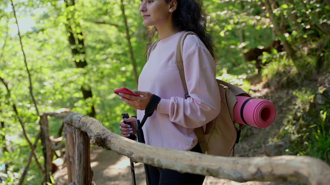 mujer caminando en el bosque con teléfono y palos de senderismo