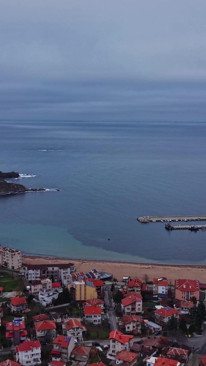 Vista panoramica della città costiera con barche ormeggiate e cielo nuvoloso sullo sfondo