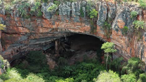 plano medio de un dron aéreo de la gran entrada de la cueva lapa doce de rocas coloridas con una selva tropical autónoma debajo en el parque nacional chapada diamantina en bahia, noreste de brasil