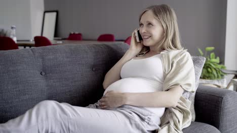 smiling pregnant woman talking on smartphone