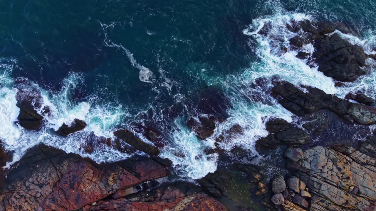 Waves crashing against rugged rocks at the coastline during sunset create a beautiful scene of nature's power and beauty