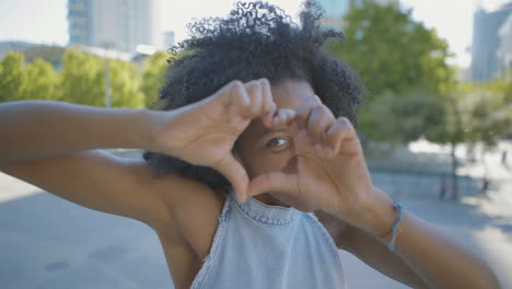 cheerful woman showing love sign outside, sending kisses