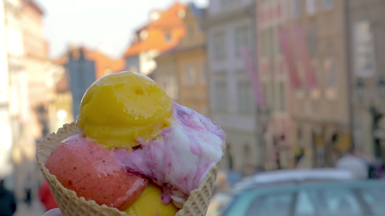 Vista al rallentatore di un paesaggio urbano sfocato sullo sfondo e poi palline di gelato in una coppetta di cialda, Praga, Repubblica Ceca