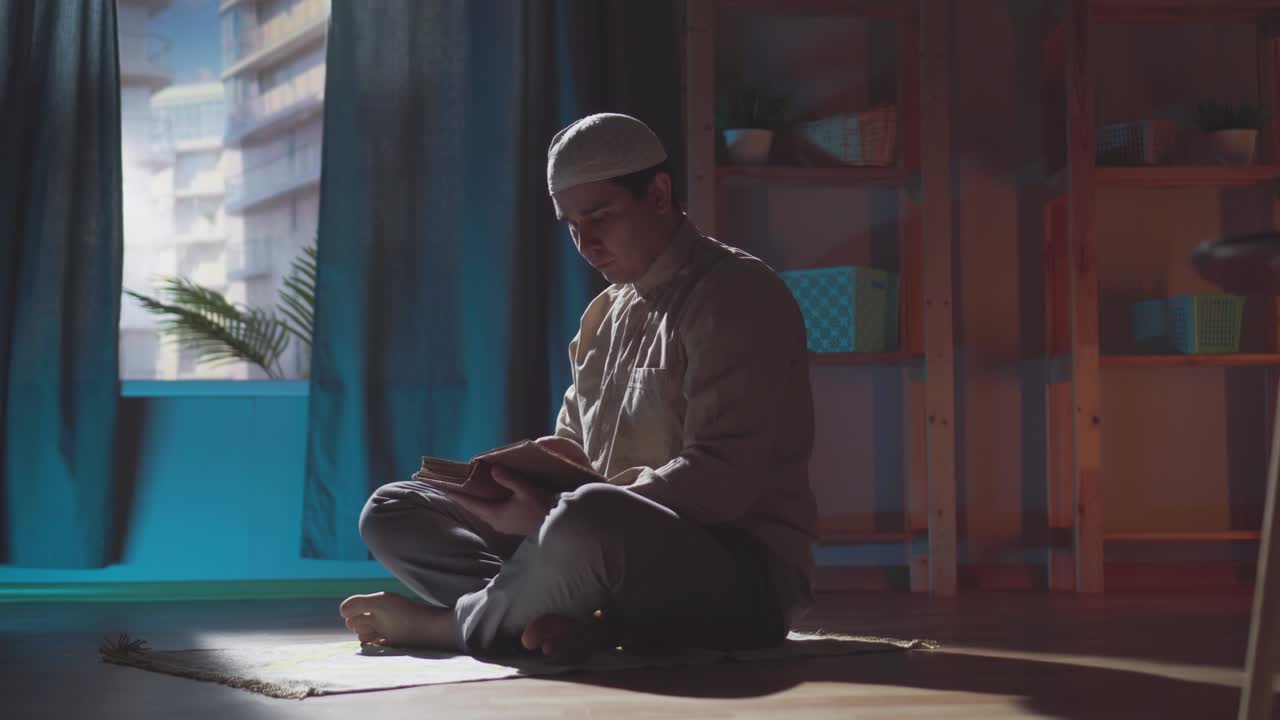 어두운 사진, 전통 옷을 입은 무슬림 남자가 집에서 책을 읽고 있습니다.