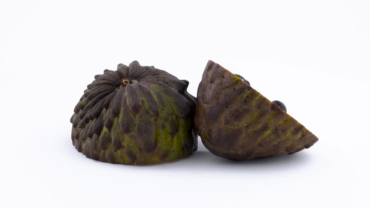 dos mitades de fruta madura de annona. pulpa de fruta de manzana de azúcar con las semillas. girando en la mesa giratoria aislada en el fondo blanco. cerca. macro.