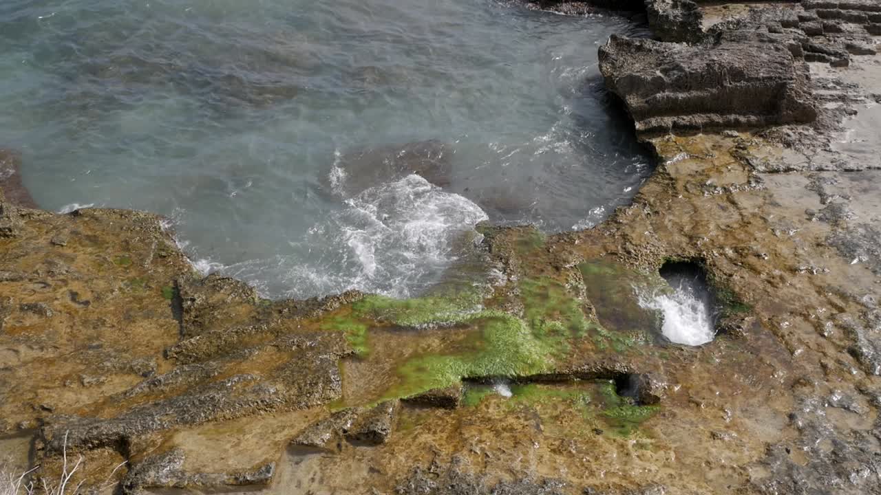 Roman baths on rocky coast with crashing waves, Calpe Spain