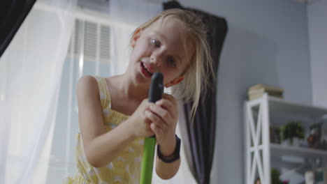 child singing with a mop as a microphone